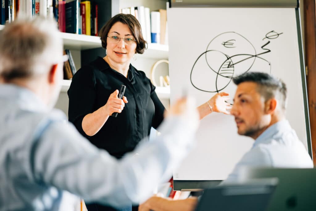 Drei Personen die auf dem Flipchart arbeiten und im Gespräch sind bezüglich SEO Resultaten in der SEO Agentur Basel